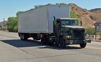 Dark Freightliner tractor-trailer driving through a Nevada town