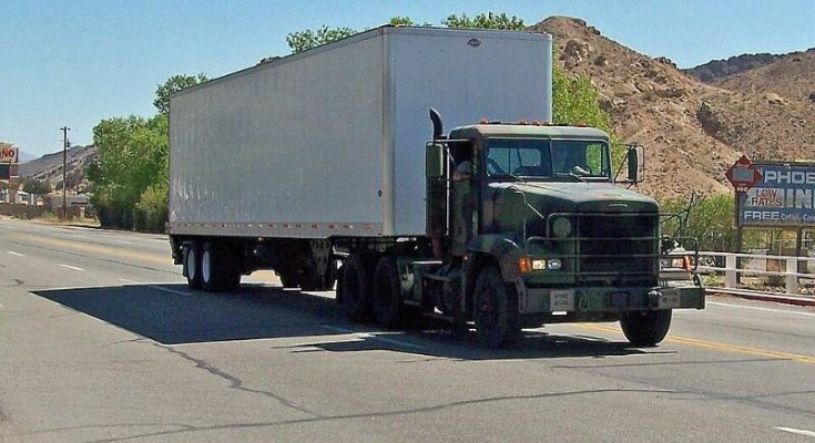 Dark Freightliner tractor-trailer driving through a Nevada town