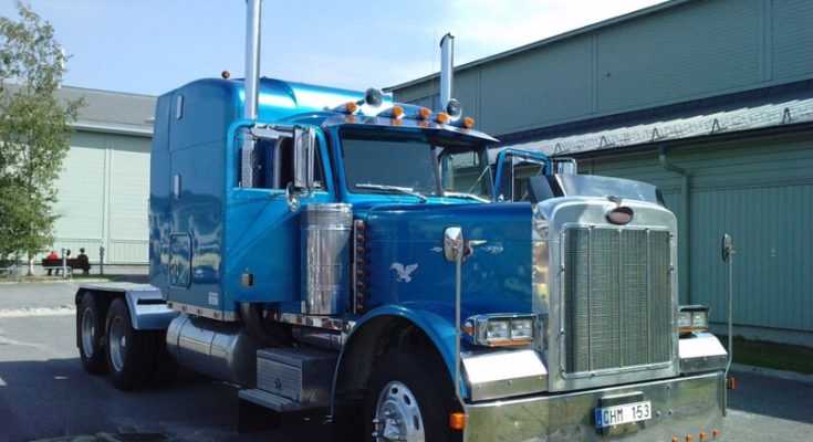 Blue Peterbilt 379 semi truck parked outside an industrial building