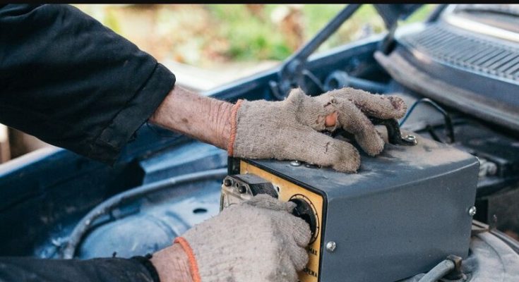 Mechanic testing a car battery under the hood