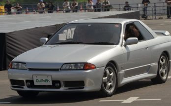 Silver Nissan Skyline R32 driving on a paved course