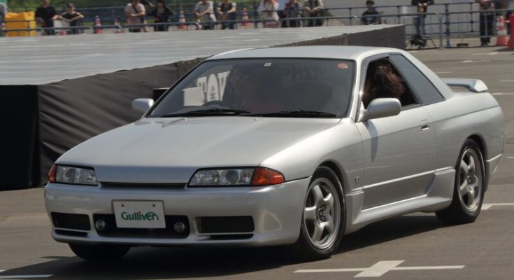 Silver Nissan Skyline R32 driving on a paved course