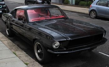 Black 1967 Ford Mustang parked on a wet street