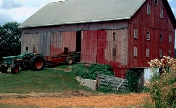 Farm tractor parked beside a large red barn in rural Ohio