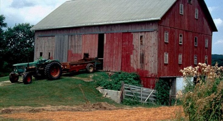Farm tractor parked beside a large red barn in rural Ohio